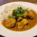 Finished Poulet Curry Coco served with rice, garnished with cilantro, ready for delicious dining.