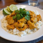 Delicious Poulet Curry served with rice, garnished with cilantro and lime, ideal for a homemade meal.