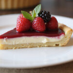 Sliced Tarte Au Fromage served on a plate, adorned with fresh berries, ideal for dessert.