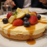 Tarte Au Fromage finie garnie de fruits frais et de sauce caramel, prĂȘte Ă ĂȘtre servie.