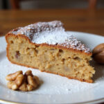 Part de gâteau aux noix parfaitement présentée avec du sucre glace, à savourer.