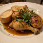 Finished Poulet Basquaise beautifully plated, accented with herbs and bread for a delightful meal.