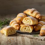 Freshly baked croissant broodjes served elegantly on a plate, showcasing their flaky and buttery texture.
