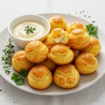 Delicious finished gougères au fromage served with dipping sauce, ideal for any occasion.